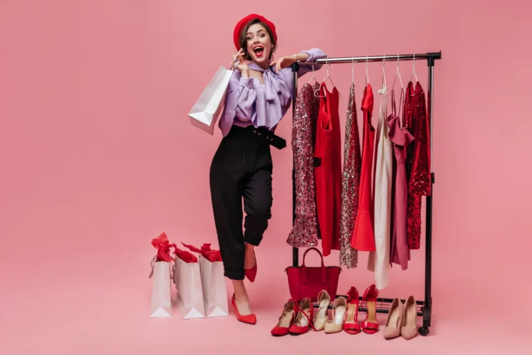 woman black trousers purple blouse laughs leaning stand with elegant clothes pink background